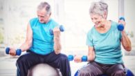 Senior people are doing exercises on the fitness balls with dumbbells