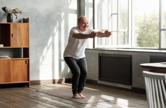 A senior man is doing yoga in the room