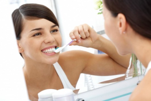 A young woman is brushing her teeth in front of the mirror in the bathroom