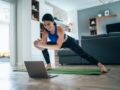 Girl is working out at home in front of the laptop using the fitness application