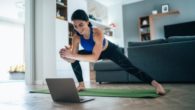 Girl is working out at home in front of the laptop using the fitness application