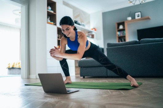 Girl is working out at home in front of the laptop using the fitness application