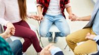 people are sitting in circle and holding hands in the rehab center