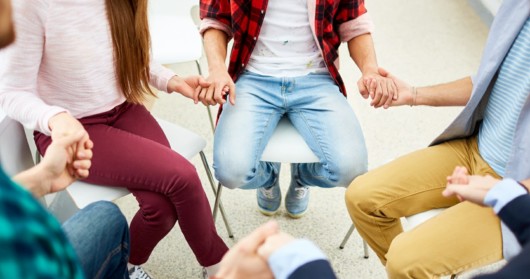 people are sitting in circle and holding hands in the rehab center