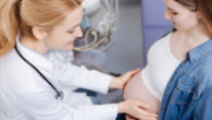 Professional obstetrician providing proficient checkup while examining pregnant belly