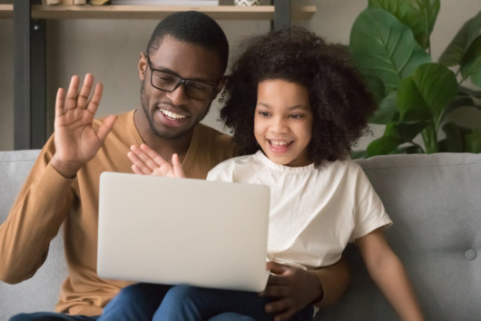 black dad with kid daughter. They are doing speech teletherapy