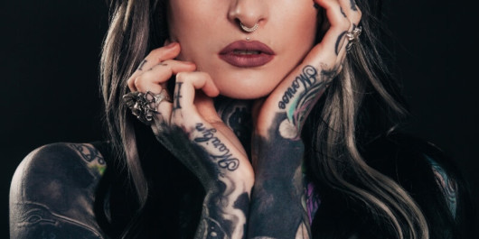 A close picture of a lady with tattooed arms and hands. Risks of tattoos