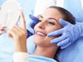 A woman is checking her teeth after cosmetic dentistry