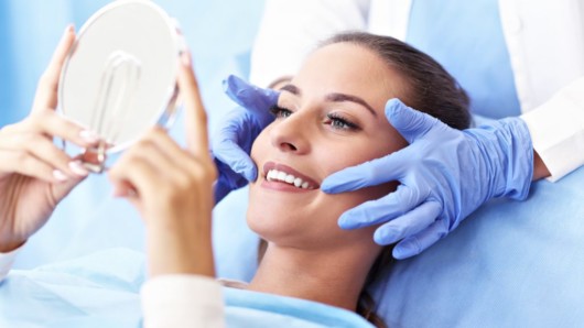 A woman is checking her teeth after cosmetic dentistry