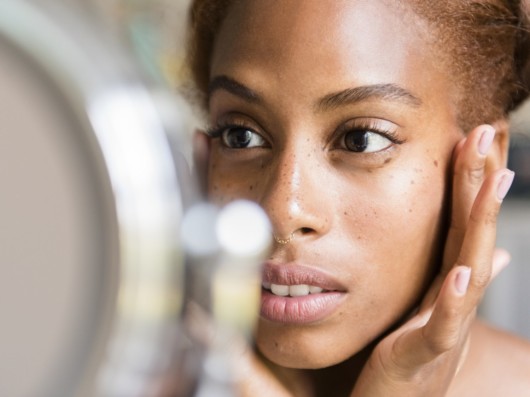 A young girl is checking her face for age related blemishes in the mirror