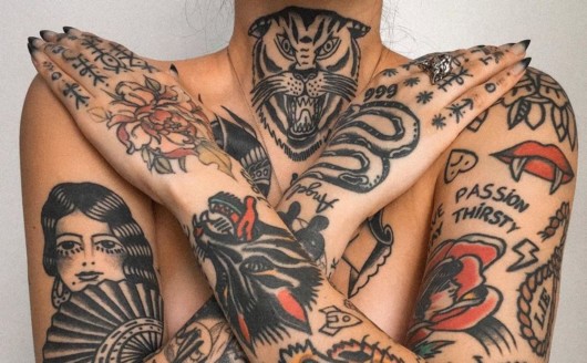 A close picture of a lady's body on white fully covered in bright tattoos