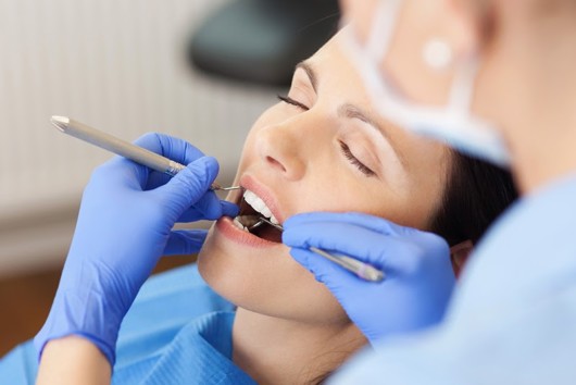 The woman is under dental sedation while the doctor is checking her teeth