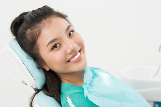 Girl is sitting at the dentist's chair and smiling