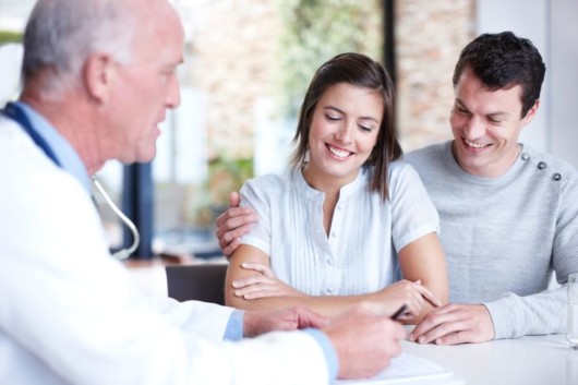 a happy couple is talking to a doctor about a fertility therapy