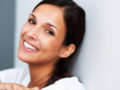 A close up fave of a beautiful woman with dark hair who is smiling on white background