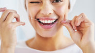 A young girl is cleaning her even teeth with a floss