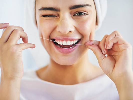 A young girl is cleaning her even teeth with a floss