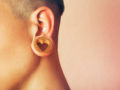A close up picture of the ear with a tunnel and a wooden earring in the shape of heart