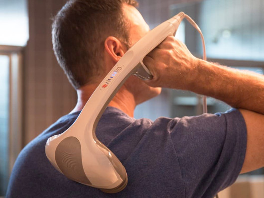 A guy is doing massage with a hand-held massager 