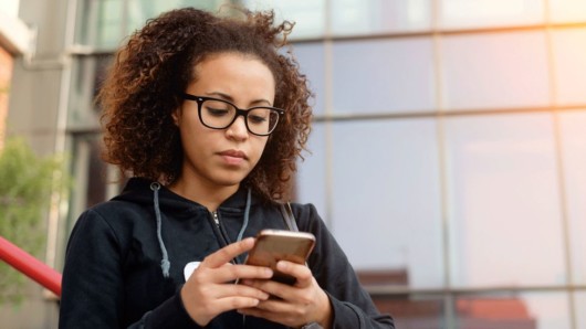 A young girl is checking her cellphone on the street