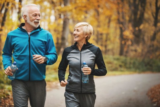 A senior couple is exercising in the park in autumn