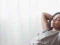 young woman is lying on the chair with closed eyes and her arms behind her back