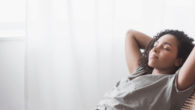 young woman is lying on the chair with closed eyes and her arms behind her back