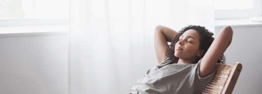 young woman is lying on the chair with closed eyes and her arms behind her back