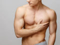 A young man with a well-built body holding his breast