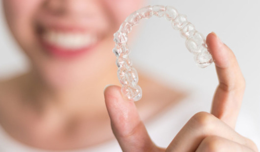 A close up picture of the invisalign trays that is hold by a blurred girl at the background
