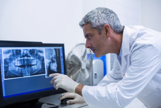 A dentist is checking the patient teeth on the computer