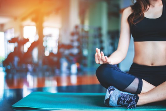 A girl is doing yoga in the gym to support her mental health