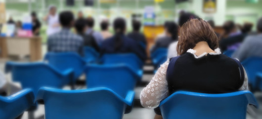 Patients are sitting in the waiting room on blue chairs