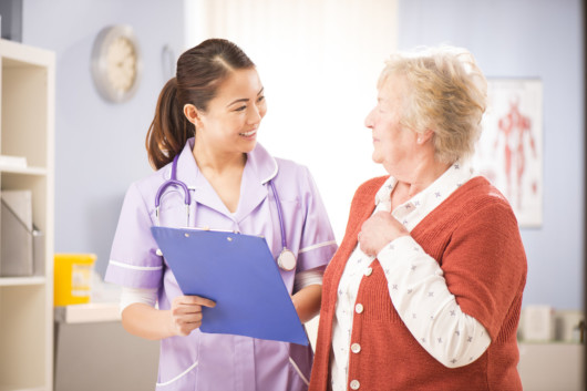 A young nurse is helping to a senior woman in the hospital