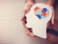 A girl is holding an image of a person's head with the brain in the shape of heart