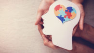A girl is holding an image of a person's head with the brain in the shape of heart