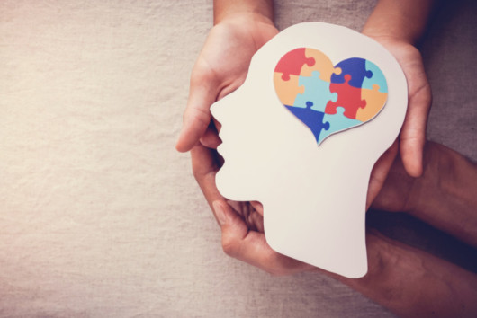 A girl is holding an image of a person's head with the brain in the shape of heart