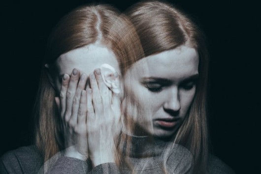 A young girl with bipolar disorder on black background