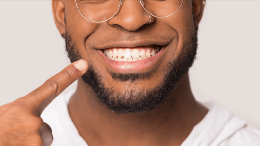 A guy on white is pointing to her even teeth