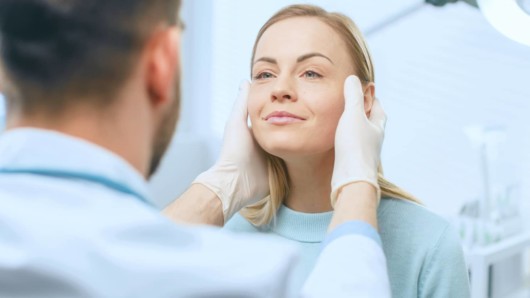 A doctor is examining a woman before facelift operation