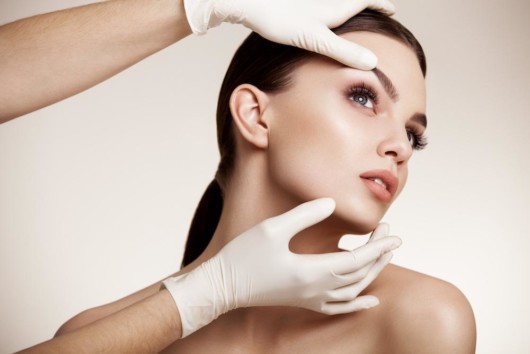 A doctor is examining a young woman after the plastic operation 