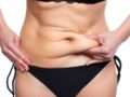 A woman is pinching her belly fat