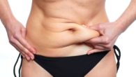 A woman is pinching her belly fat