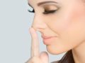 A beautiful woman with closed eyes is touching her nose with a finger
