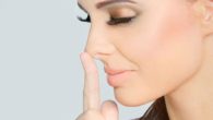 A beautiful woman with closed eyes is touching her nose with a finger