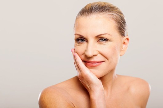 A nice looking woman on light background holding her face in her hand