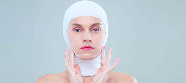 A young woman with a bandage around her head after the plastic surgery