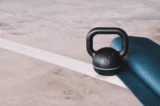 A kettle bell and a training mat on the floor A kettle bell and a training mat on the floor