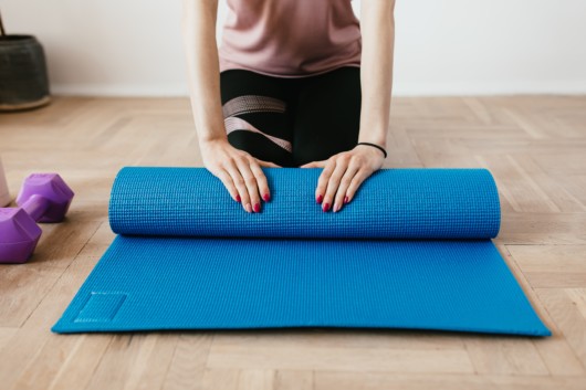 A woman rolling out a gymnastic mat