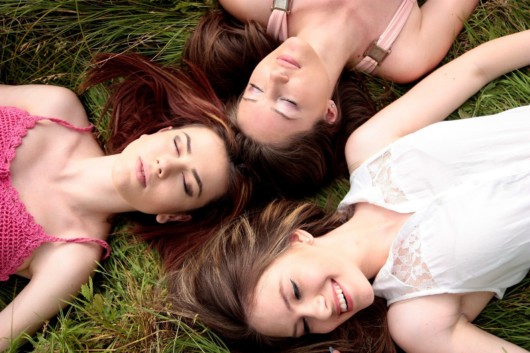 three relaxed women lying on green grass
